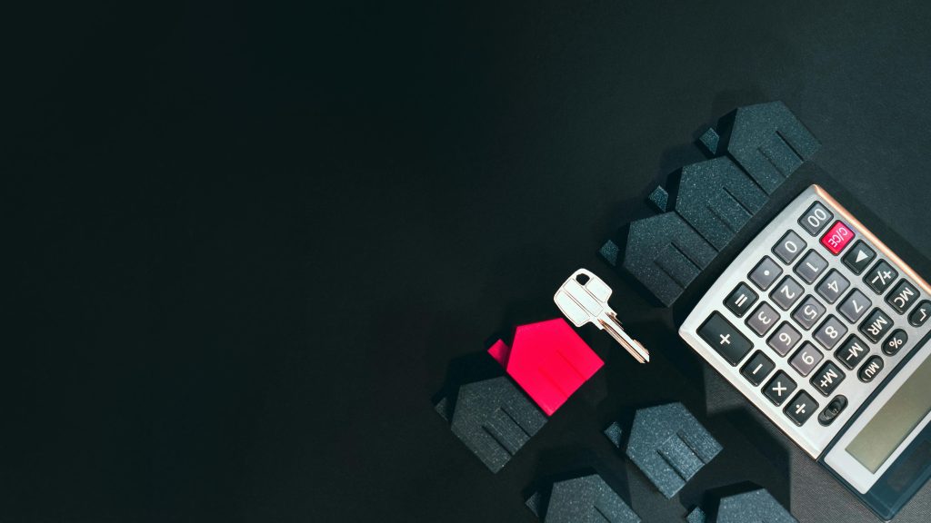 House keys, calculator, and small house model on a finance background
