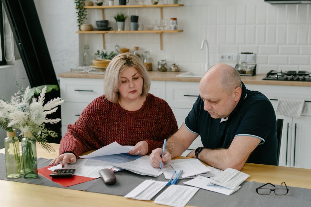 A couple sitting at a kitchen table reviewing real estate documents together
