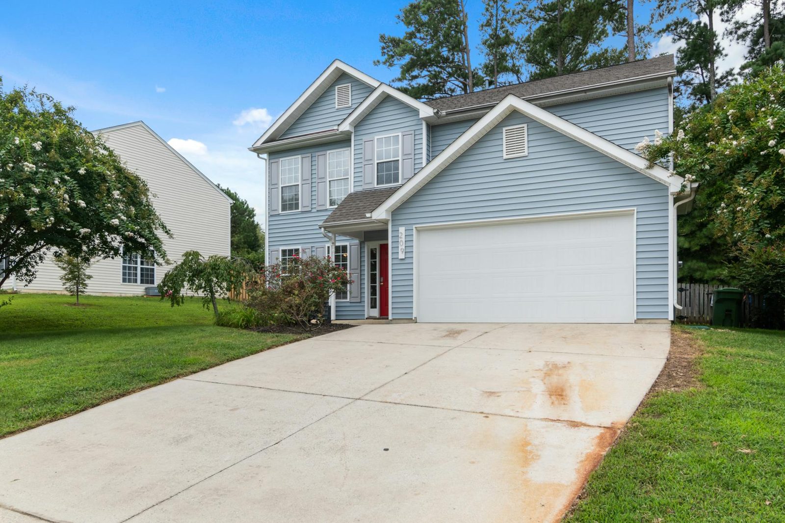 Sunny suburban home with manicured front yard in summer — the season most buyers transact in, and the season most likely to produce a deal they later regret.