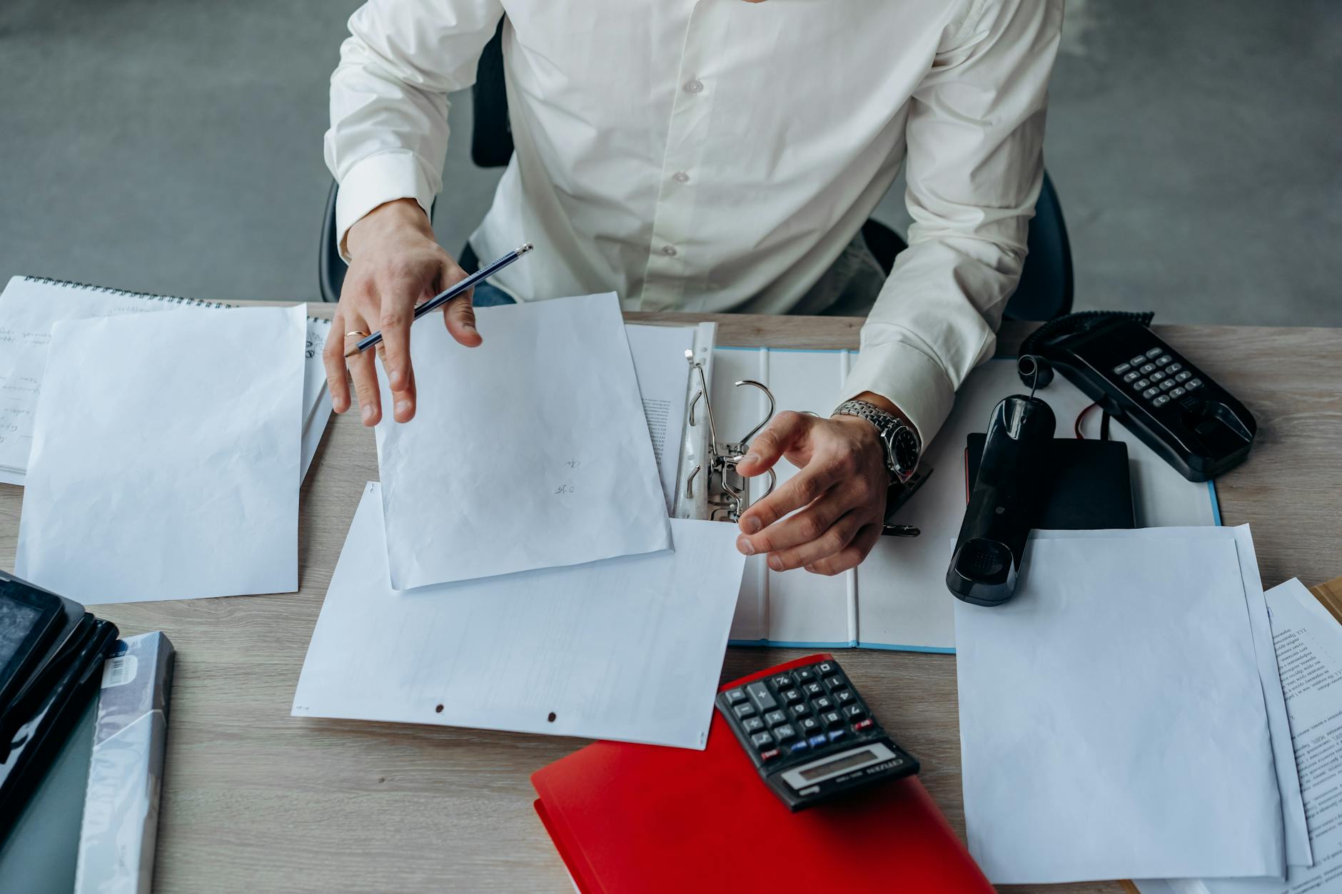 Borrower at a desk with a stack of organized documents — preparing the document set proactively before applying for a mortgage.