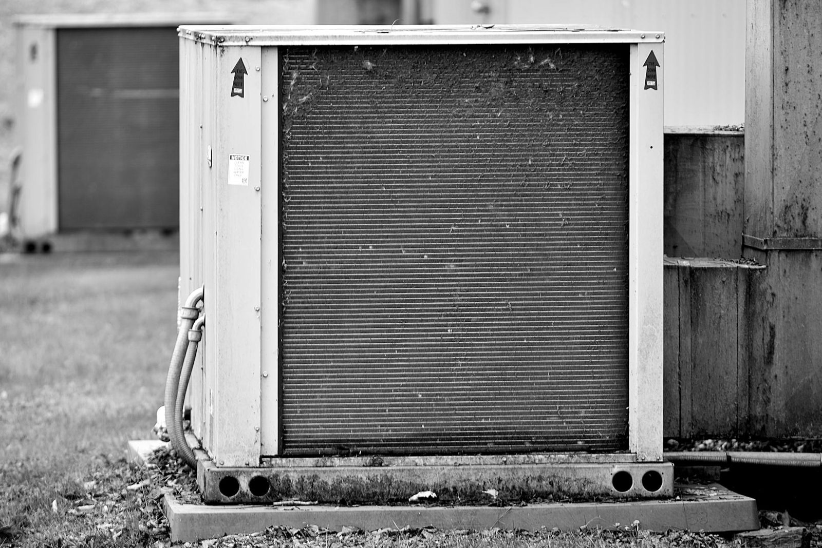 Home inspector checking the outdoor HVAC condenser unit — summer is the best season to verify cooling performance under peak load.
