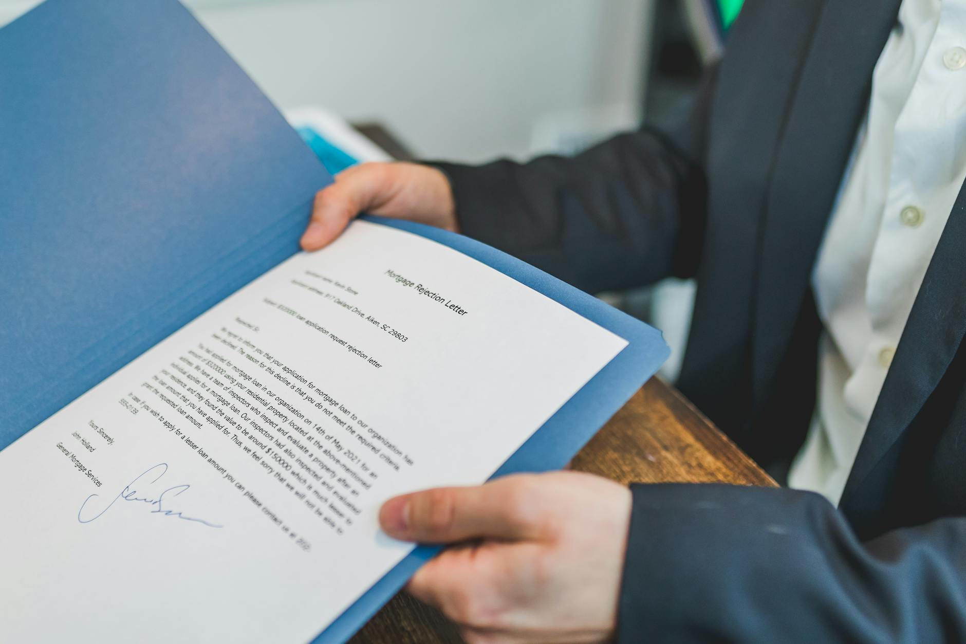 Buyer signing mortgage closing documents at a closing table.