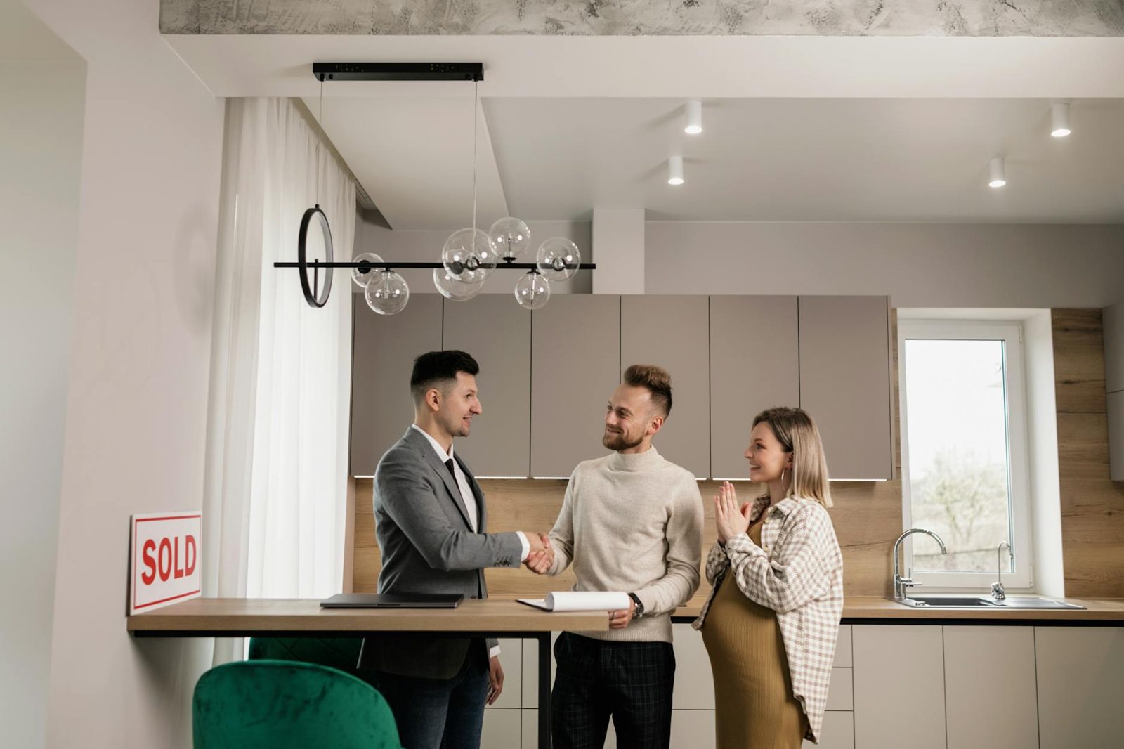New homeowners signing closing documents at a table — the payoff for a prepared summer purchase.