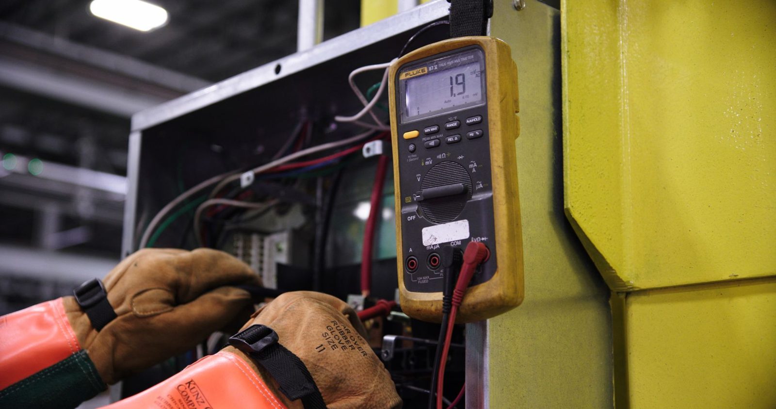 An inspector examining an open electrical panel — the kind of safety hazard an inspection surfaces.