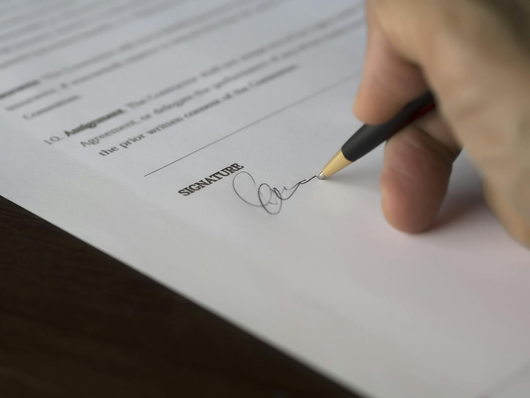 A person quickly signing paperwork — the rushed, casual way most people choose a real estate agent.