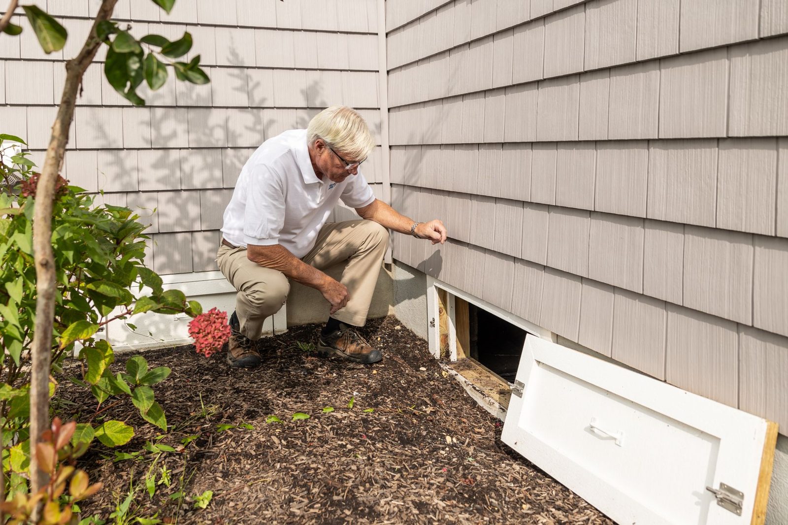 An inspector shining a flashlight into a crawl space — a reminder that inspections only see what's accessible.