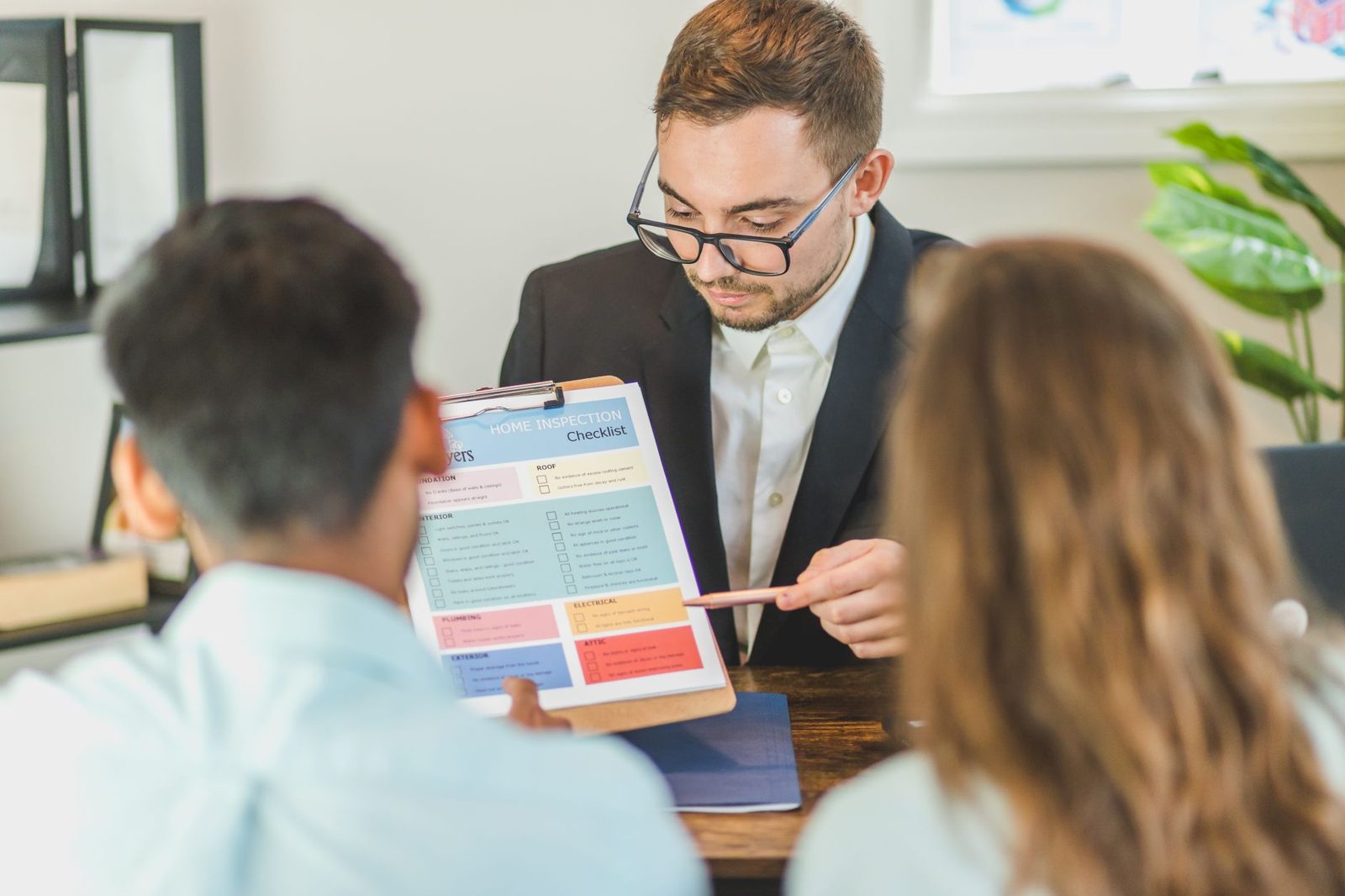 Homebuyers reviewing an inspection report with their agent at a table, sorting findings by what matters.