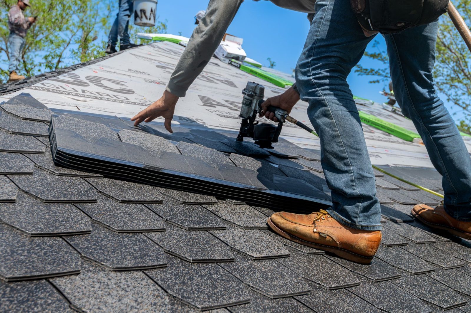 Roofing crew installing new asphalt shingles on a residential home