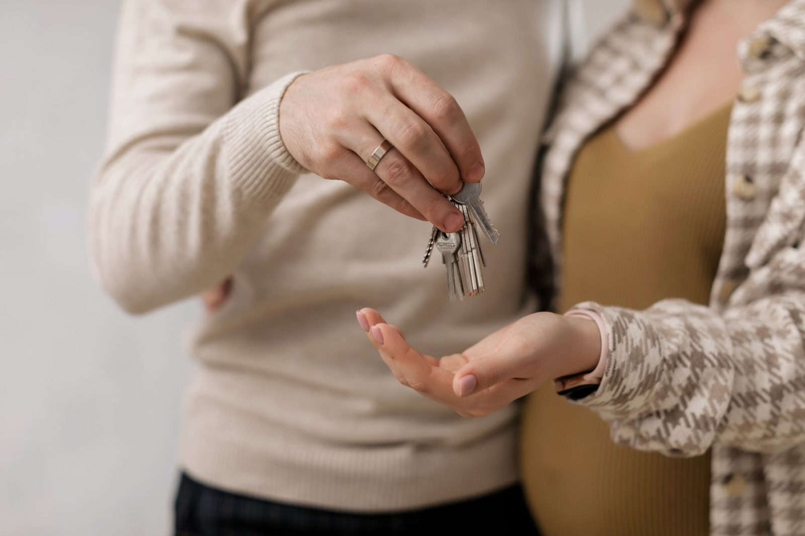 Relaxed new homeowners holding keys outside their home — the payoff of buying within their means.