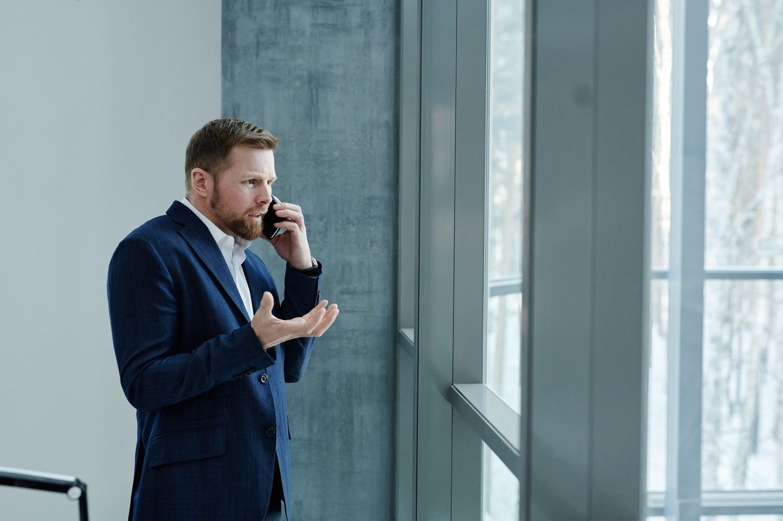 Person on a phone call near a window looking concerned about a real estate update
