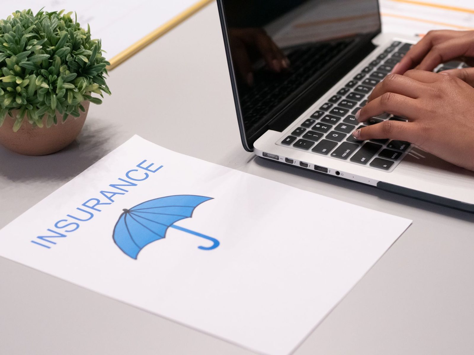 Person comparing printed insurance quotes side by side at a desk.