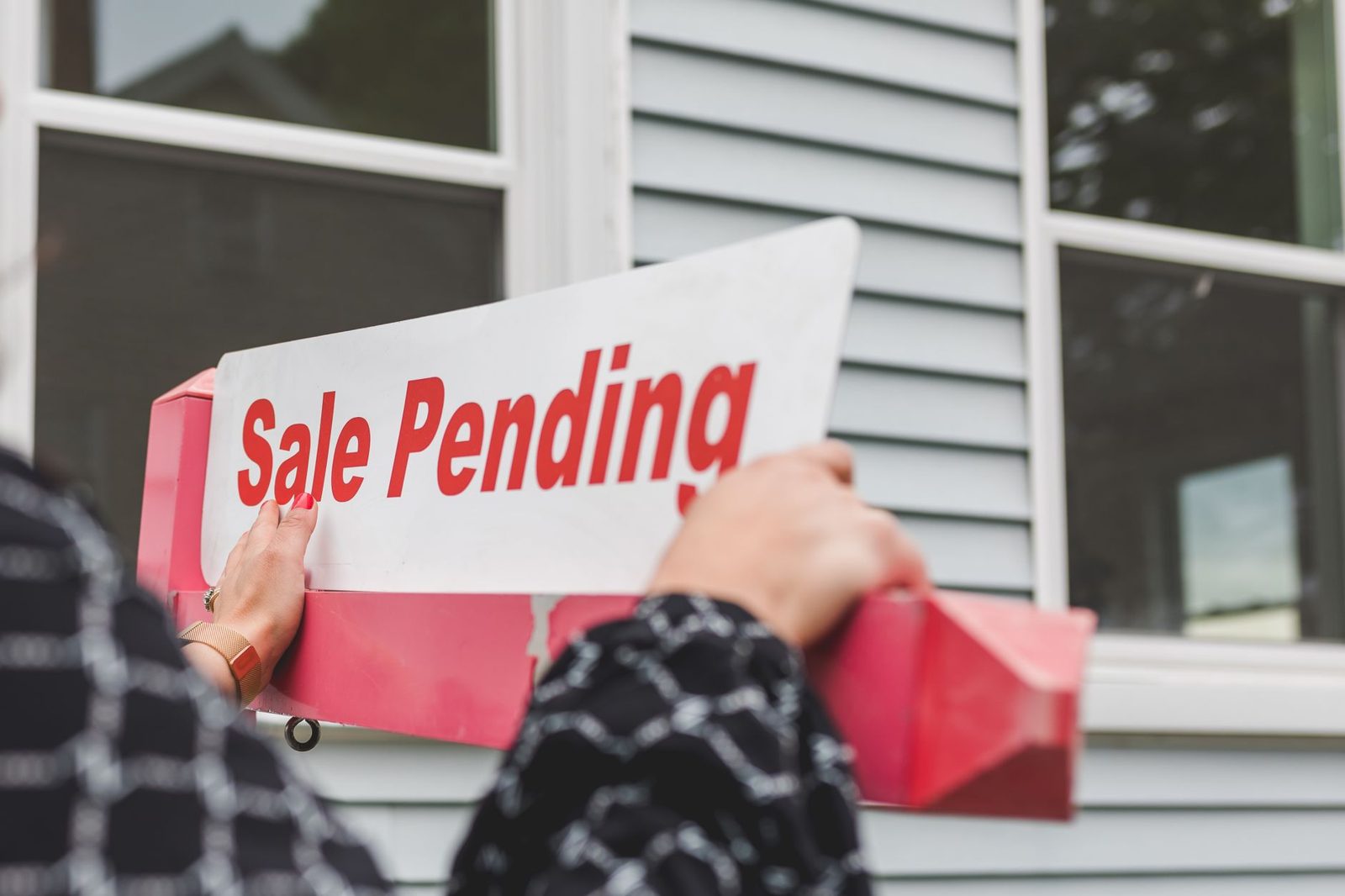 A real estate for-sale sign with an additional status rider attached beneath it