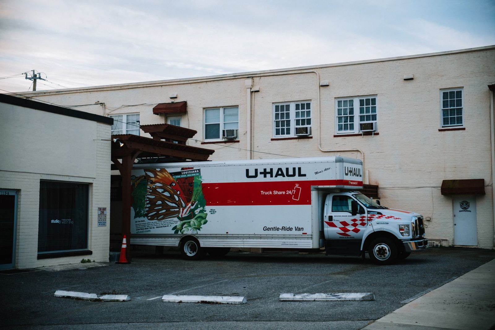 A moving truck parked in the driveway of a house during a transition