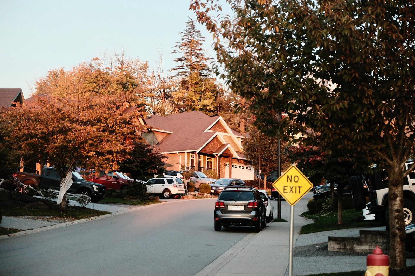 Family standing near their car and house, representing bundled home and auto insurance.