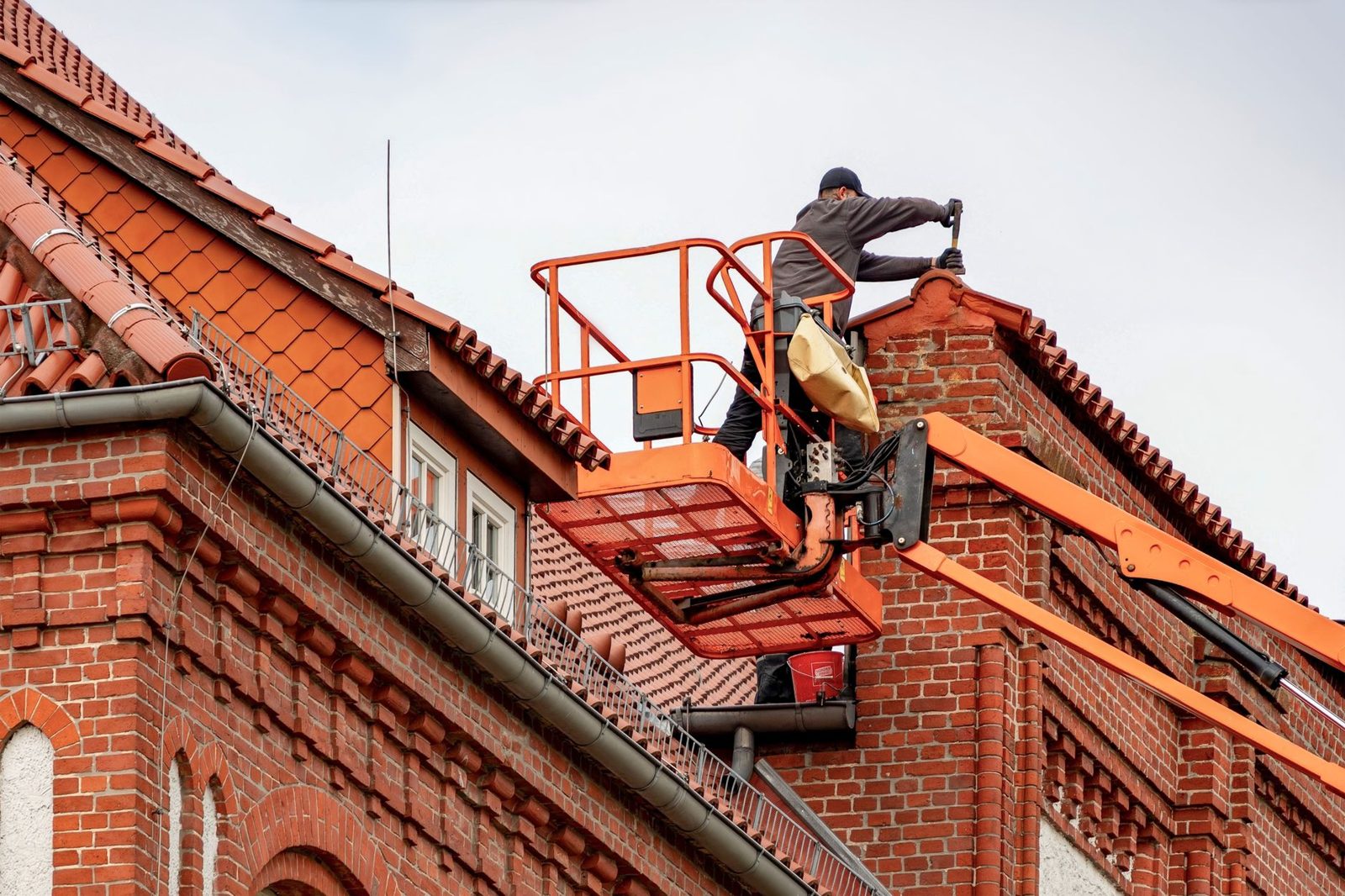 Homeowner cleaning gutters from a ladder with safety precautions